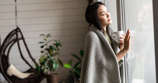 woman with a cape on looking out the window